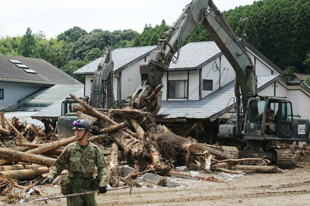Defence forces soldiers remove debris in a flooded area in Asakura, Fukuoka prefecture on July 9, 2017. / AFP.
