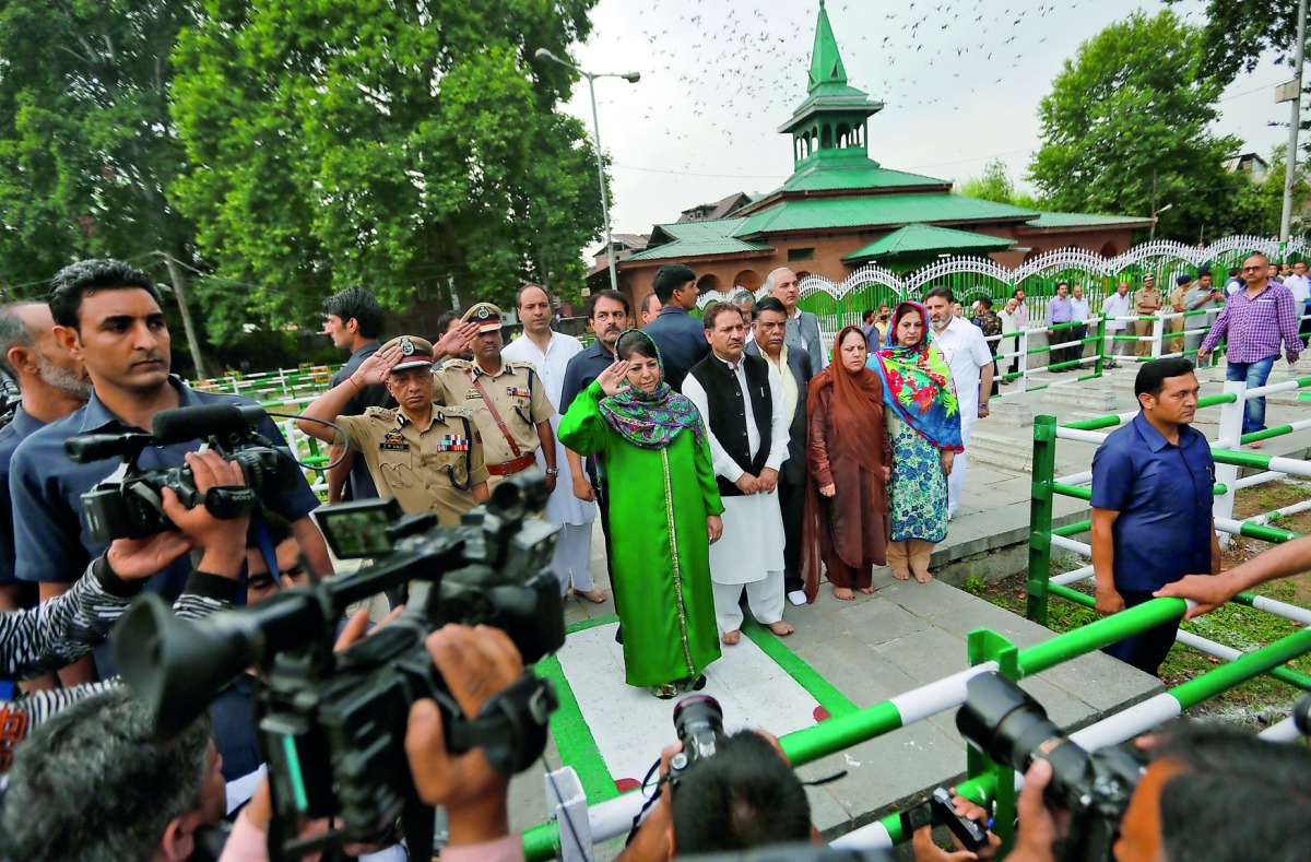 Jammu and Kashmir Chief Minister Mehbooba Mufti (in green) salutes at the martyrs' graveyard during an event to mark 