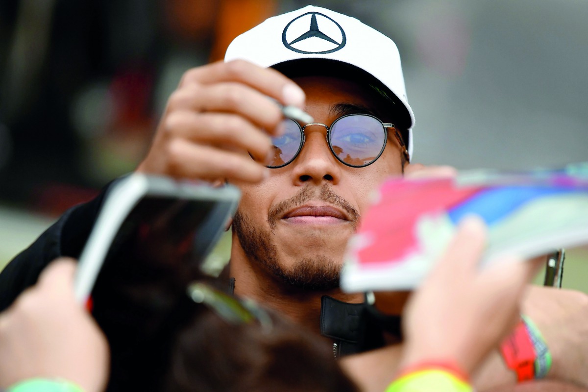 Mercedes' British driver Lewis Hamilton signs autographs for fans.