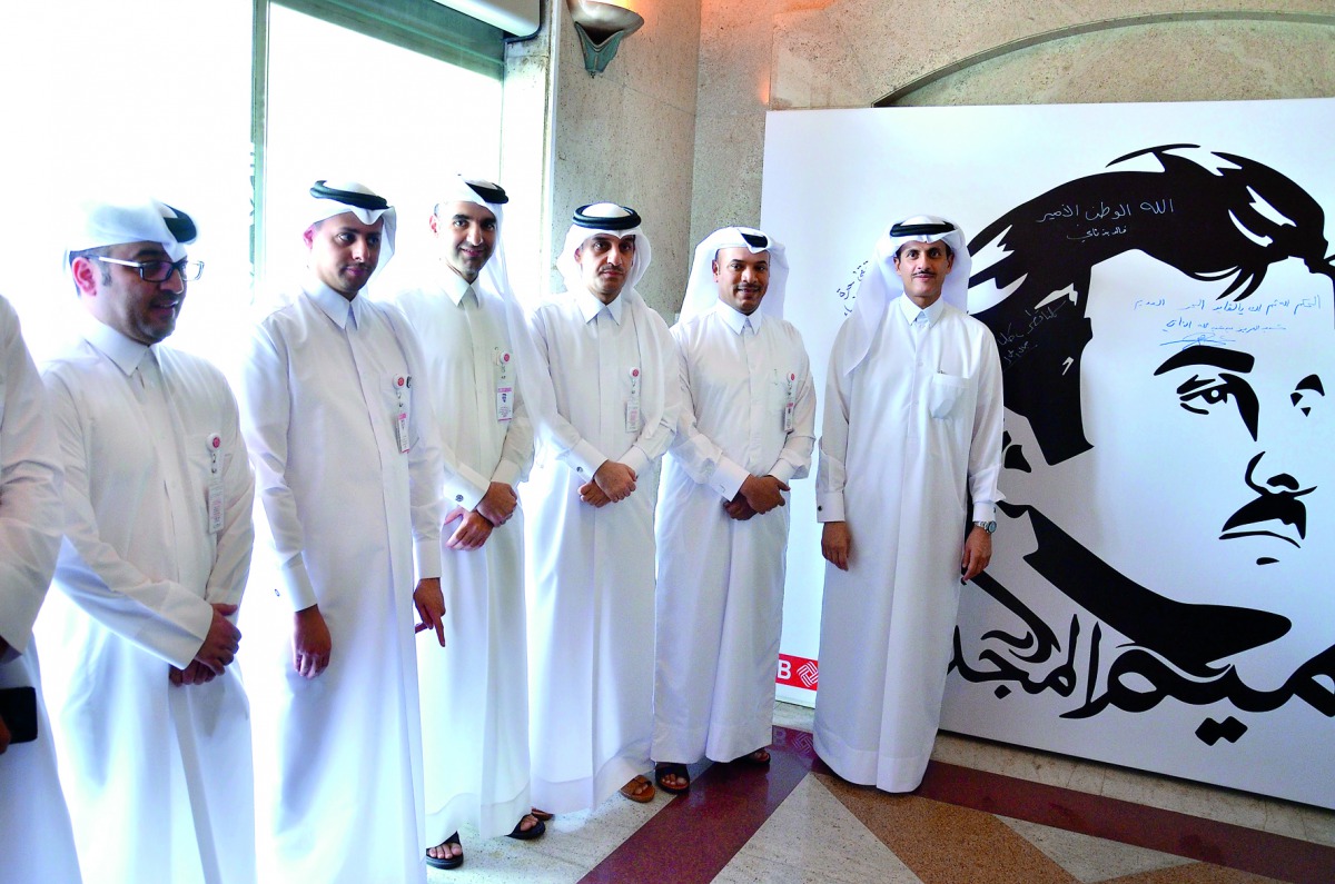 Sheikh Dr Khalid bin Thani bin Abdullah Al Thani, Chairman and Managing Director of QIIB, and Jamal Abdullah Al Jamal, Deputy CEO, with other officials at the launch of Tamim Al Majd mural yesterday. 
