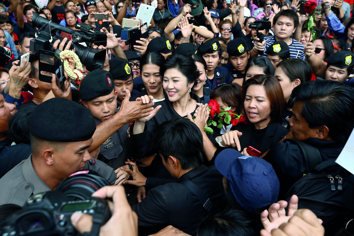 Ousted Thai prime minister Yingluck greets her supporters as she leaves the Supreme Court in Bangkok, Thailand, yesterday.