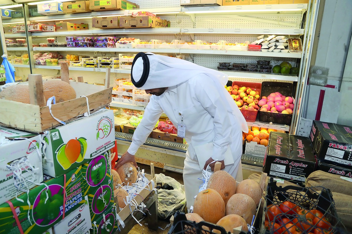 The Ministry of Economy and Commerce official conducting inspection at a fruit and vegetable shop in Doha.