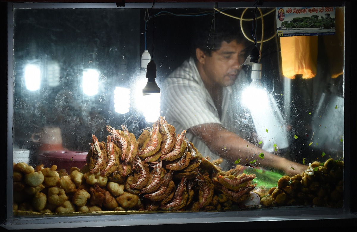 In this photograph taken on on July 23, 2017, a man sells food near the Galle fort at night in Galle.  AFP /  Ishara S Kodikara