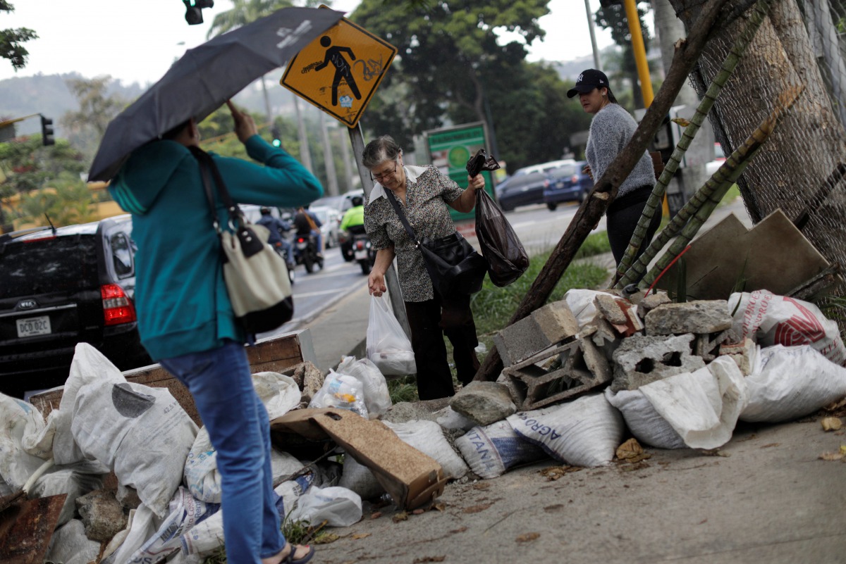 A woman walks through a barricade after a strike called to protest against Venezuelan President Nicolas Maduro's government in Caracas, Venezuela, July 28, 2017. (REUTERS/Ueslei Marcelino)