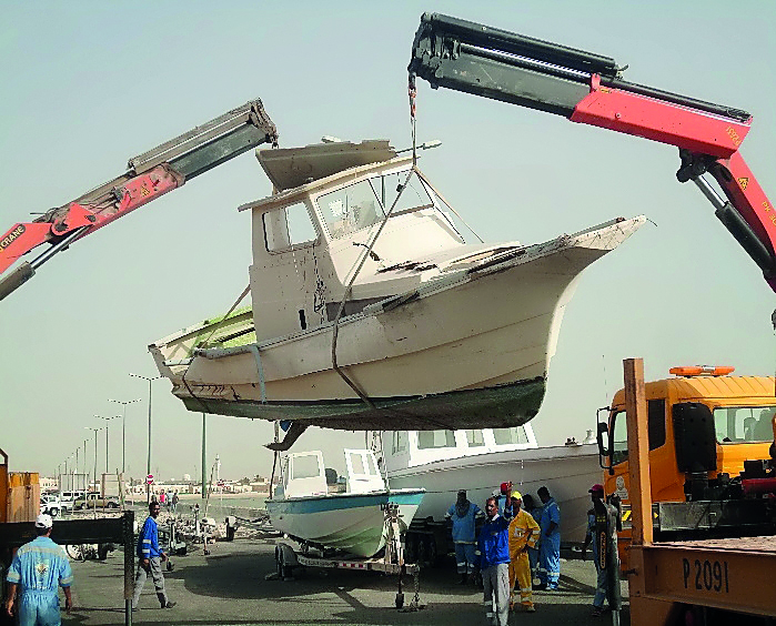 An abandoned motorboat is being removed from a port.