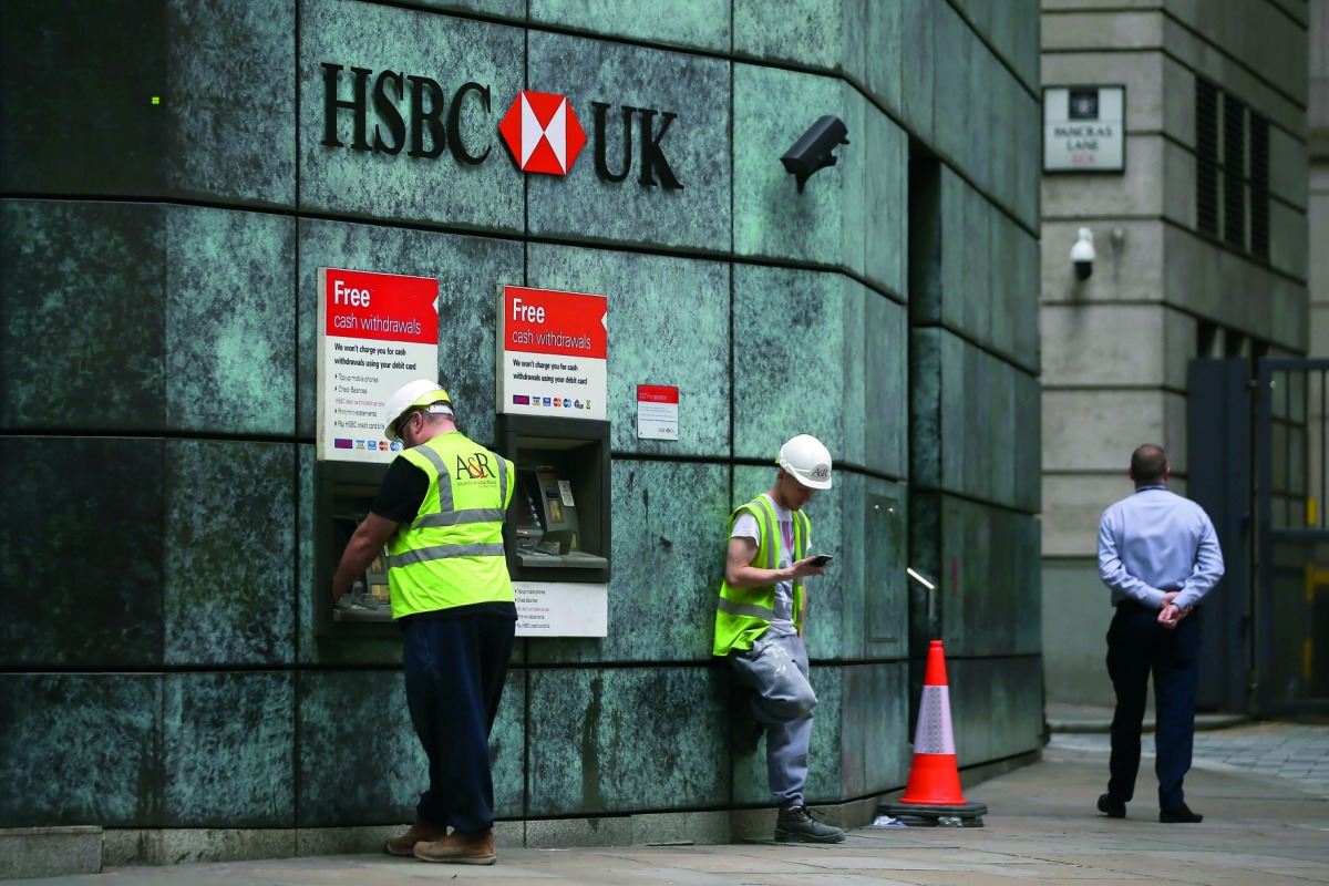 Customers use ATMs outside a branch of a HSBC bank in London, yesterday.