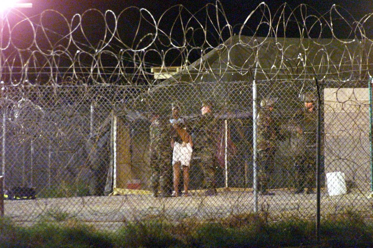 Marines at Camp X-Ray at the Naval Base at Guantanamo Bay, Cuba escort a newly arriving detainee into a processing tent after being showered in this February 7, 2002 file photo. REUTERS/Marc Serota