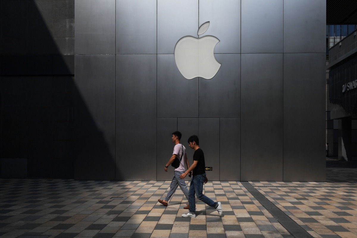 This photo taken on August 3, 2017 shows people walking past an Apple store in Beijing. AFP / Greg Baker