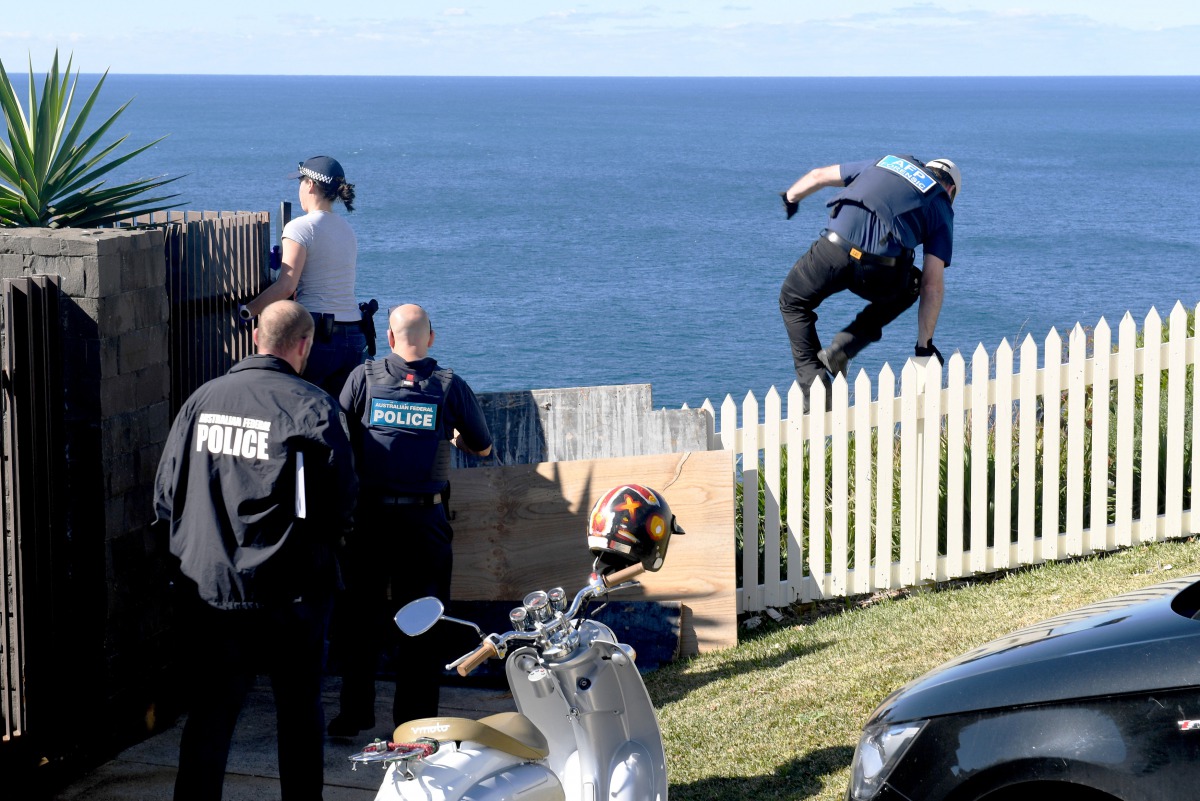 A policeman jumps a fence at the home of John Ibrahim during a police operation in Sydney, Australia, August 8, 2017. (AAP/Brendan Esposito/via REUTERS)