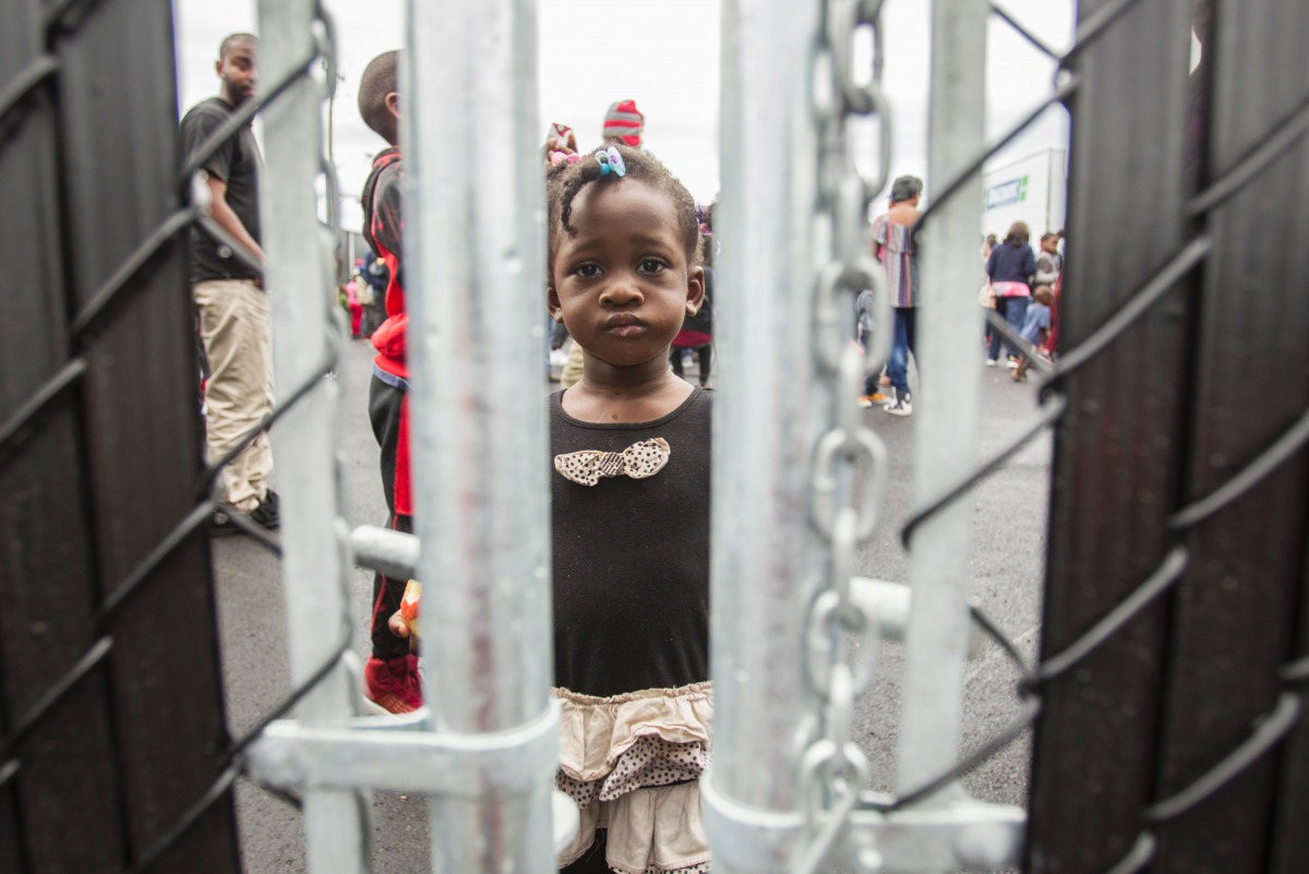 A girl who crossed the Canada-US border with her family, claiming refugee status in Canada,as she looks through a fence at a temporary detention centre in Blackpool, Quebec on August 5, 2017. AFP / Geoff Robins