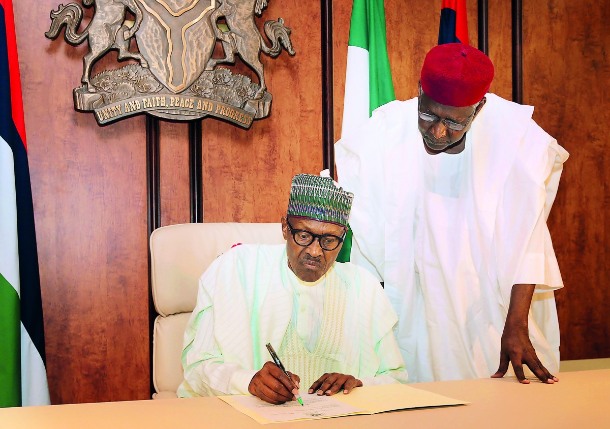 Nigerian President Mohammadu Buhari sitting beside his Chief of Staff Abba Kyari as he writes to the National Assembly, notifying the legislature of his return to office, after a medical vacation from London, in Abuja, yesterday.