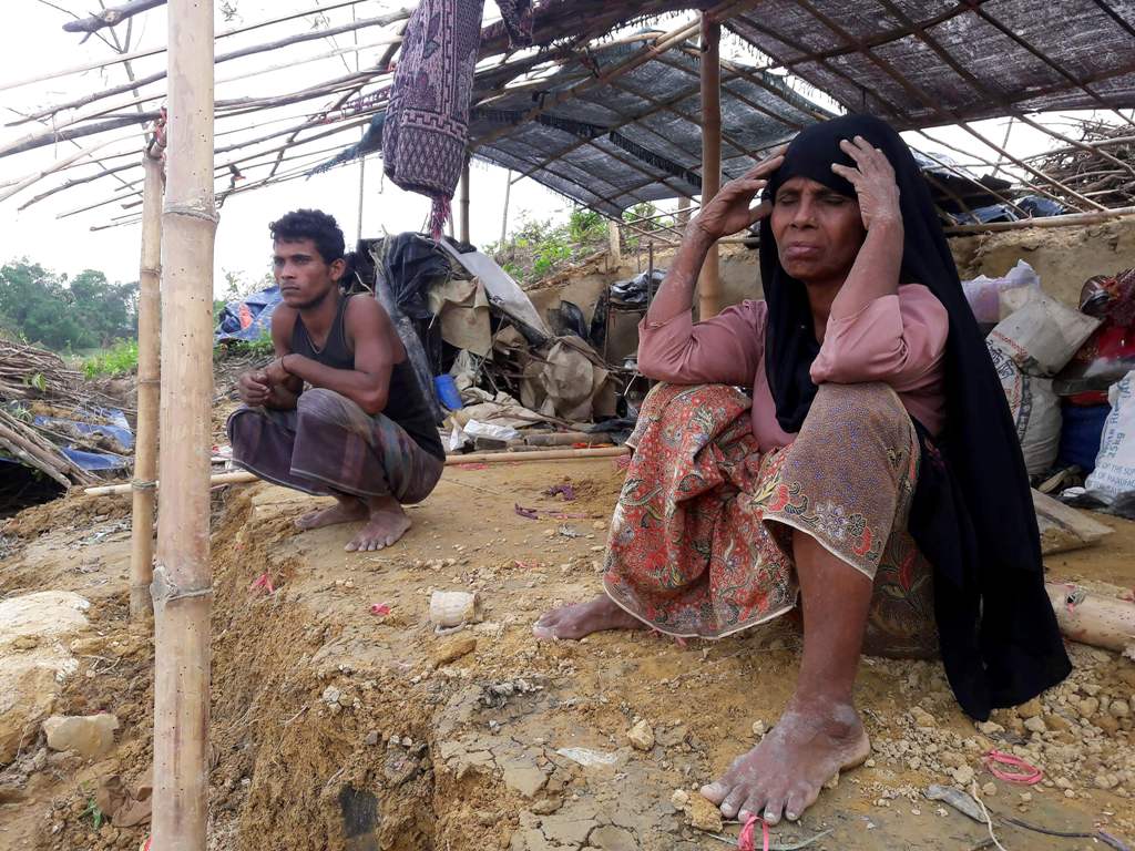 (FILES) This file photo taken on May 31, 2017 shows Rohingya refugees sitting near a house destroyed by Cyclone Mora in a camp in the Cox's Bazar district.   AFP / STR
