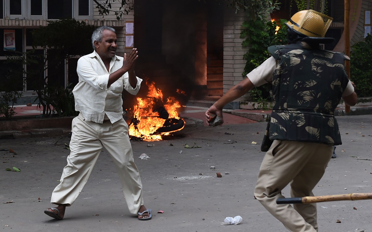 A follower of Indian religious leader Gurmeet Ram Rahim Singh pleads for his safety after being hit with a stick during clashes between the controversial guru's followers and security forces in Panchkula on August 25, 2017.  AFP / Money Sharma

