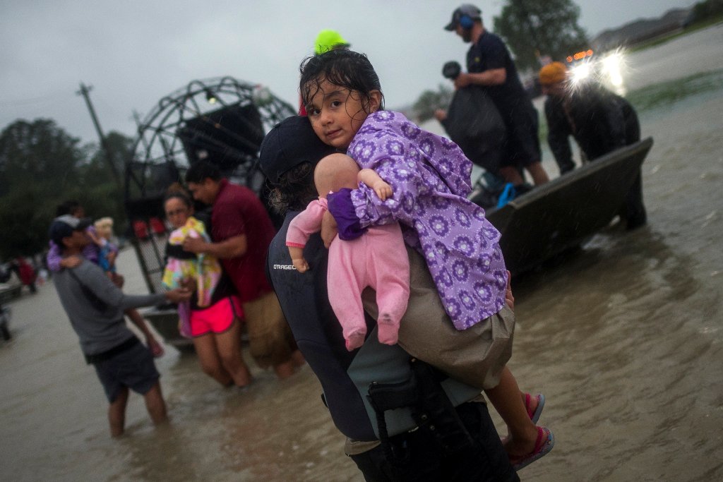 A woman holds a girl as her family arrives to high ground by boat due to floods caused by Tropical Storm Harvey along Tidwell Road in east Houston, Texas, U.S. August 28, 2017. REUTERS/Adrees Latif.