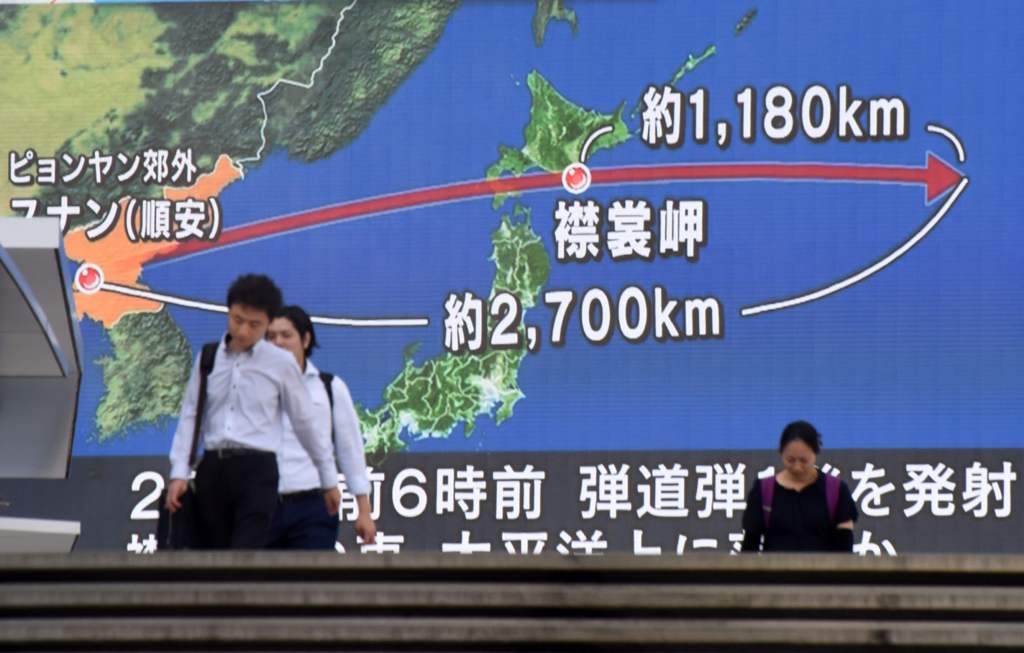 TOPSHOT - Pedestrians walk in front of a huge screen displaying a map of Japan (R) and the Korean Peninsula, in Tokyo on August 29, 2017, following a North Korean missile test that passed over Japan.  AFP / Kazuhiro NOGI
