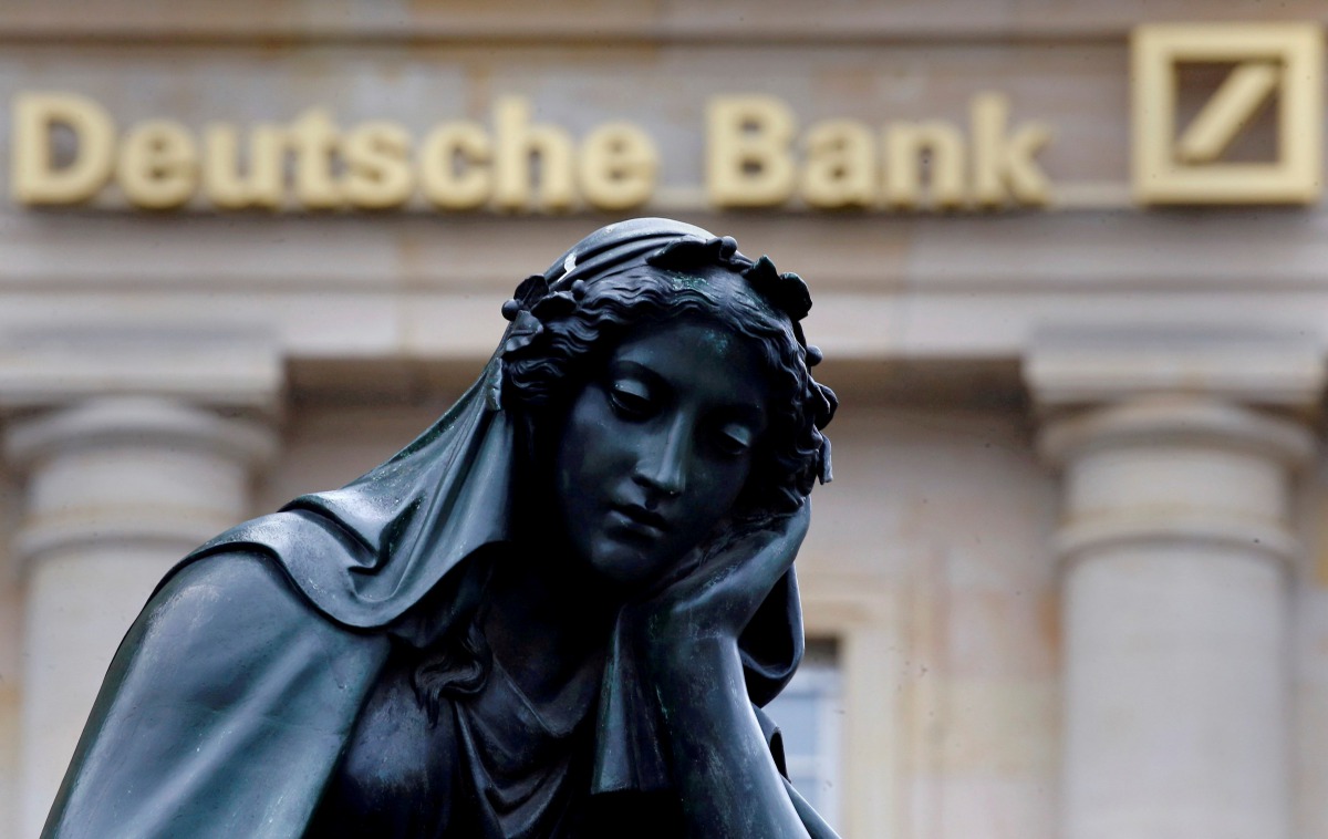 A statue is seen next to the logo of Germanys Deutsche Bank in Frankfurt (REUTERS / Kai Pfaffenbach) 