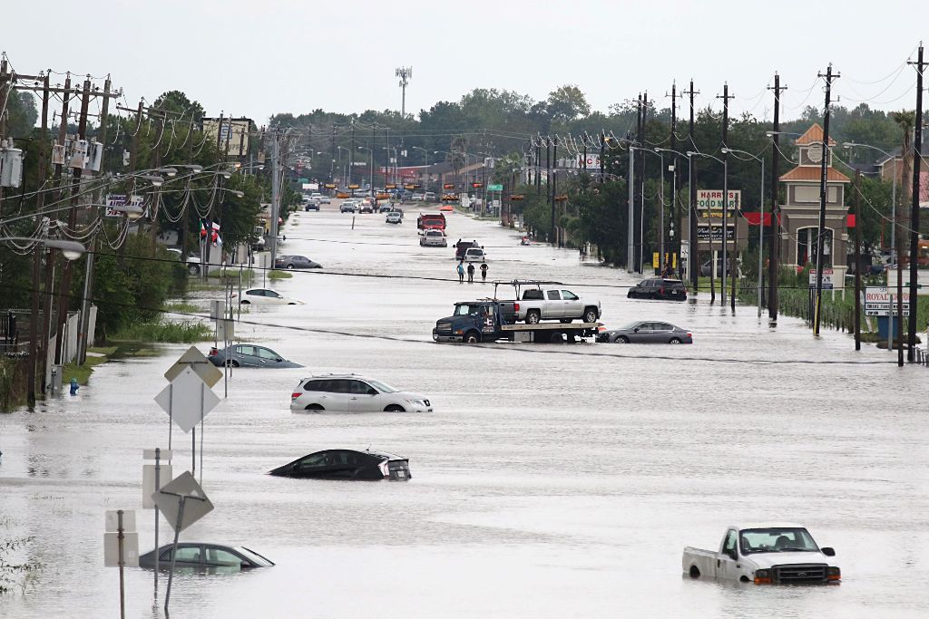 A car gets towed while men walk in the flooded waters of Telephone Rd. in Houston, Texas on August 30, 2017. Monster storm Harvey made landfall again Wednesday in Louisiana, evoking painful memories of Hurricane Katrina's deadly strike 12 years ago, as ti