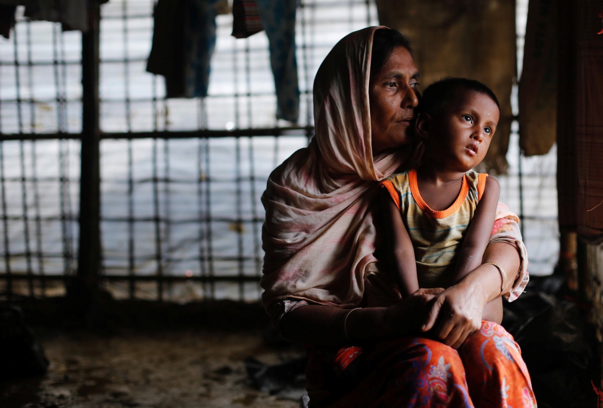 A Rohingya refugee woman waits for aid with her grandson inside their temporary shelter at a camp in Cox's Bazar, Bangladesh September 19, 2017. Reuters/Danish Siddiqui