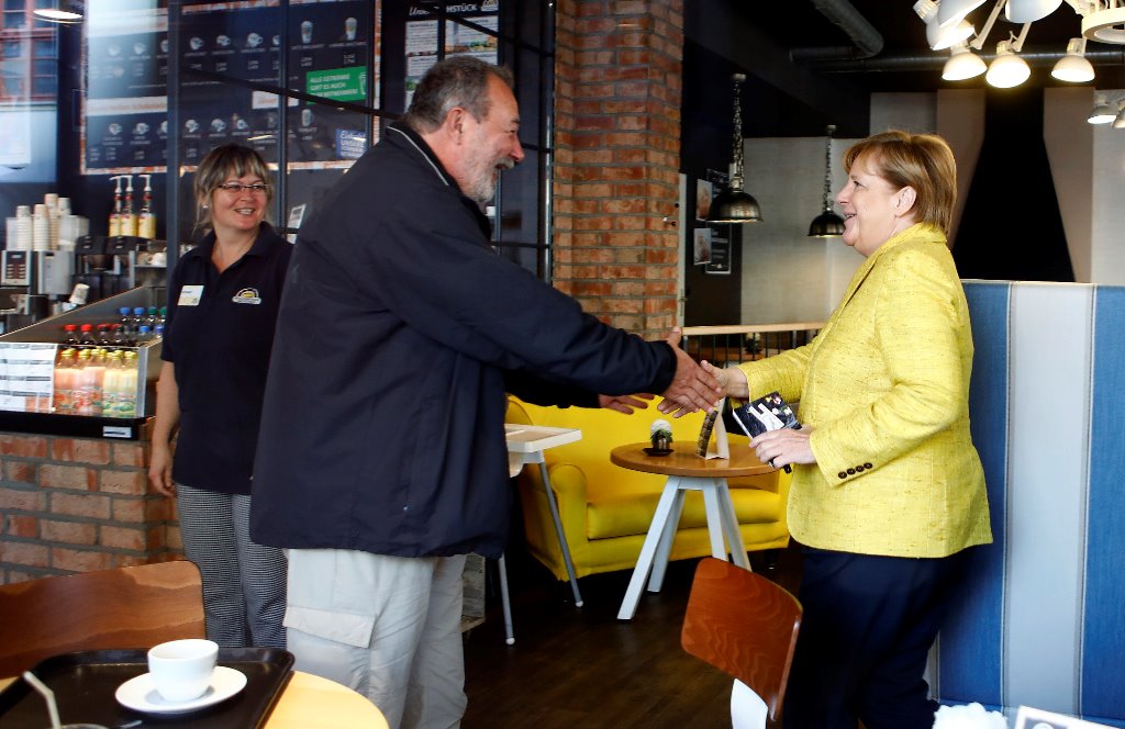 German Chancellor Angela Merkel speaks to a man inside a coffee shop during the final Christian Democratic Union (CDU) party campaign in Stralsund, Germany, September 23, 2017. Reuters/Axel Schmidt
