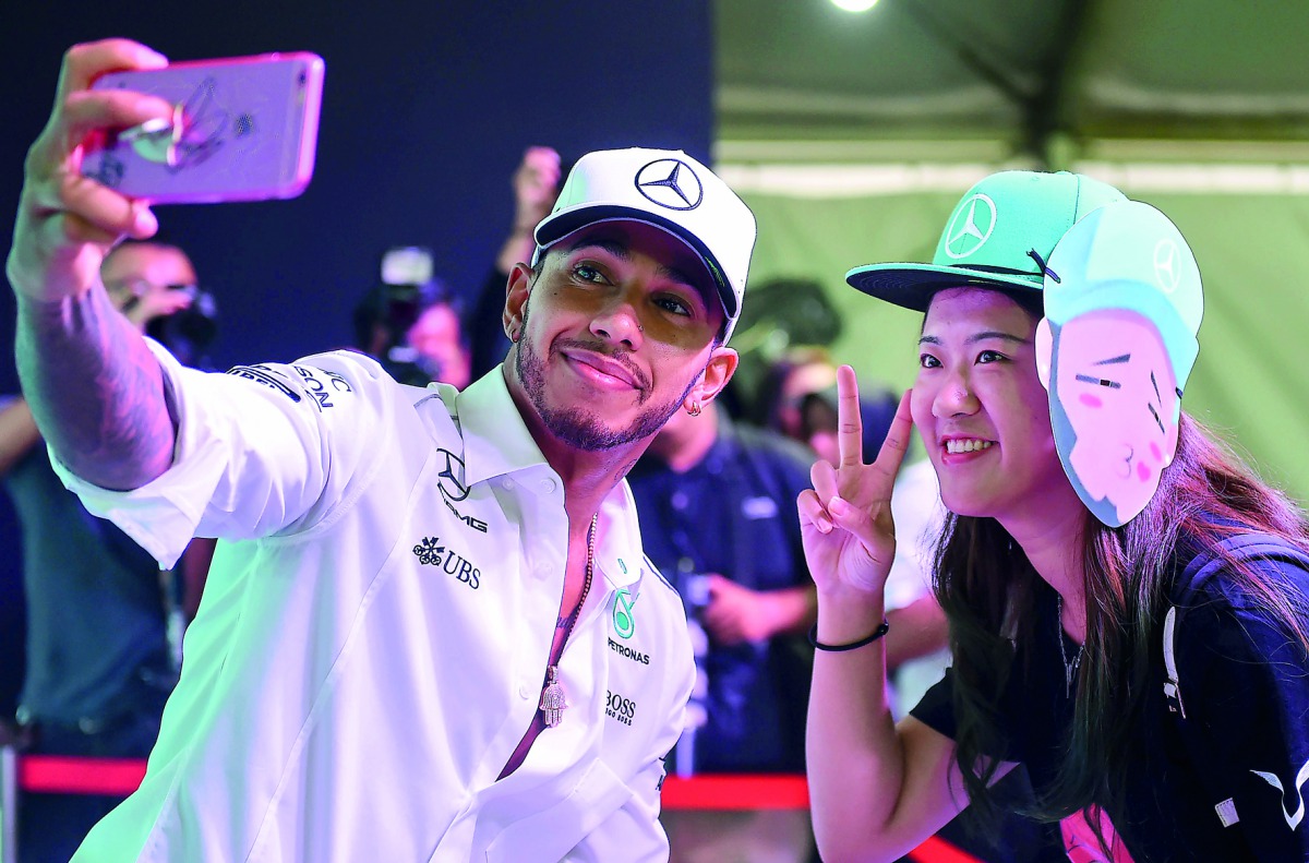 Mercedes’ British driver Lewis Hamilton (left) takes pictures during a meet the fans session in Kuala Lumpur, yesterday, ahead of the Malaysia Grand Prix. The Malaysia Grand Prix will take place on October 1.