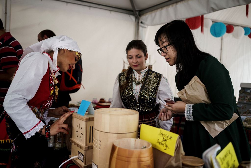 A Chinese tourist (R) speaks with Bulgarian participants during the third Chinese-Bulgarian yoghurt festival in the village of Momchilovtsi on September 8, 2017. AFP / Dimitar DILKOFF
