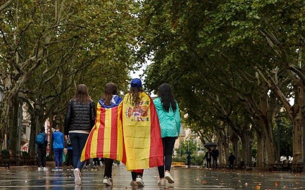 Girls stroll through the center of Figueras with the Spanish and a pro-independence 'Estelada' Catalan flag on September 30, 2017 in Figueras (AFP PHOTO / CESAR MANSO).