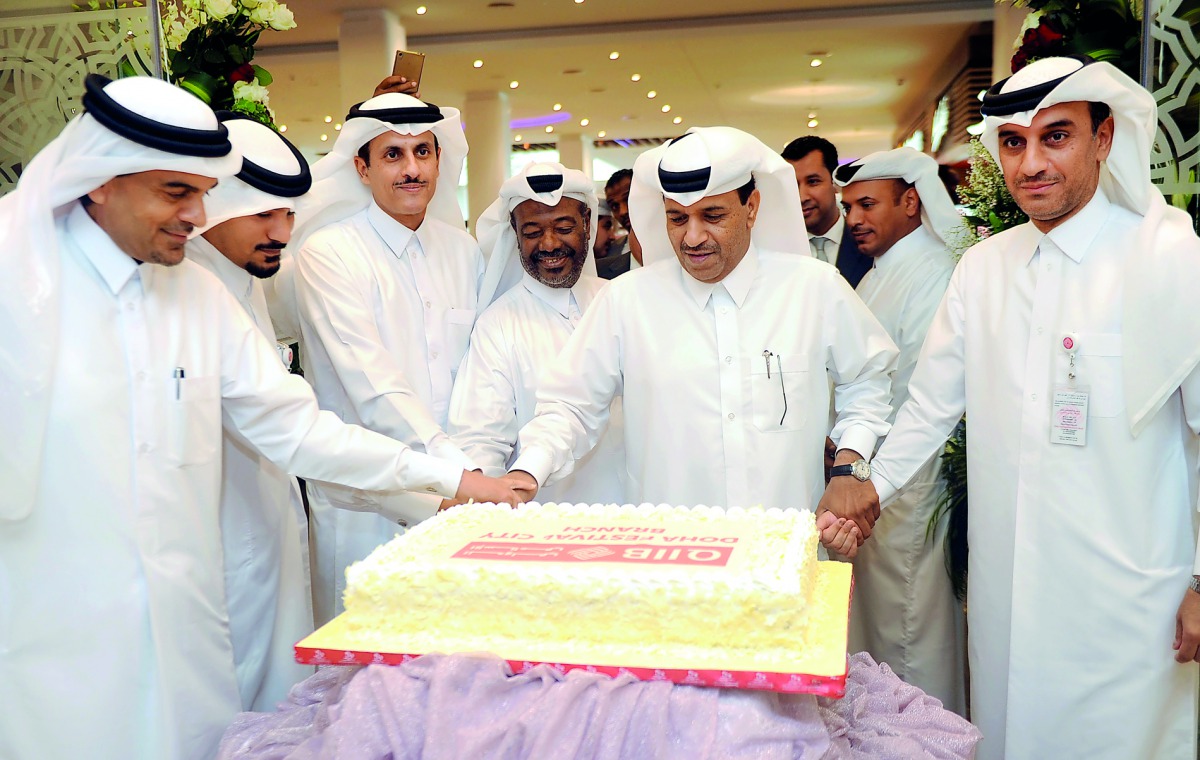 Sheikh Dr Khalid bin Thani bin Abdullah Al Thani (third left), Chairman and Managing Director, QIIB; Dr Abdulbasit Ahmed Al Shaibei (left), CEO, along with other officials and guests cutting a cake to mark the opening of the bank’s branch at Doha Festival