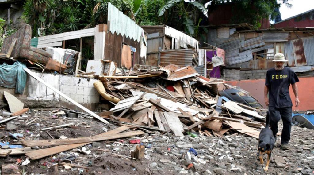 A man and a dog walk amid the rubble after Tropical Storm Nate struck the Los Anonos neighborhood in San Jose, Costa Rica. Photo: AFP.