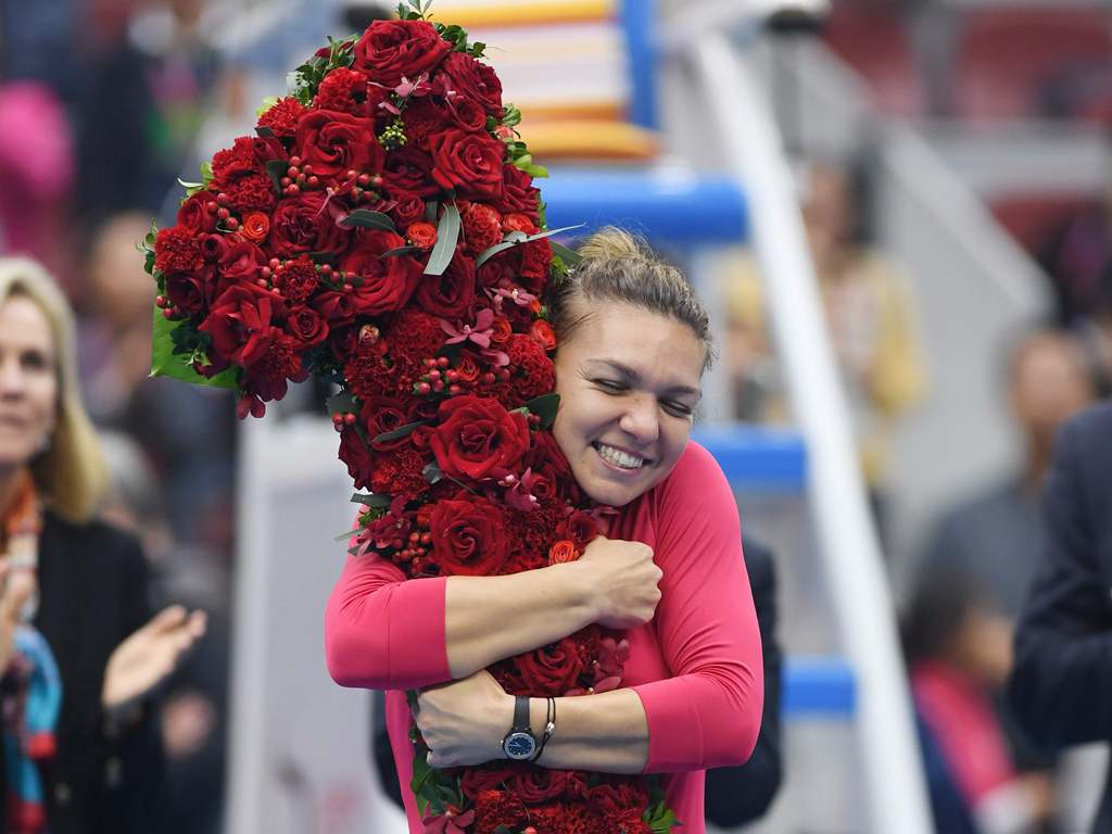 Simona Halep of Romania celebrates after being presented with a bouquet in the shape of the number '1', after taking the top ranking by winning her women's singles semi-final match against Jelena Ostapenko of Latvia at the China Open tennis tournament in 