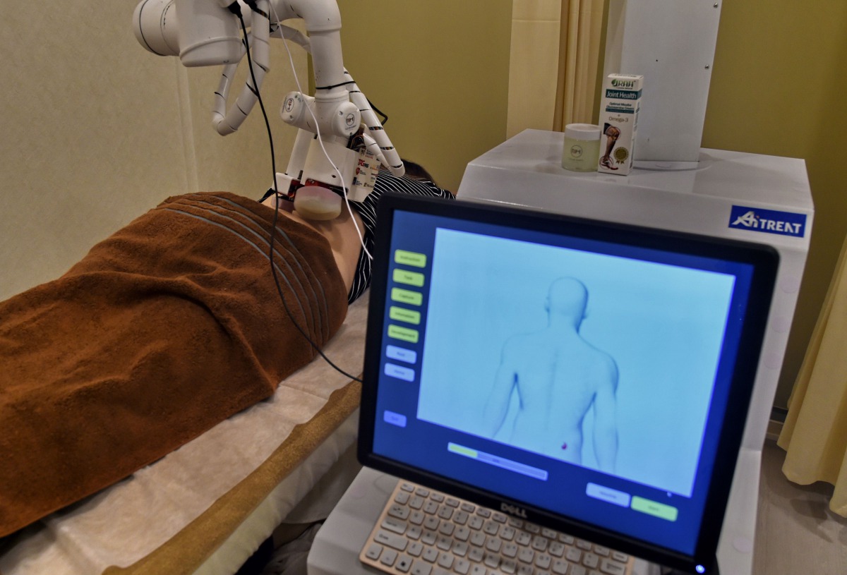 In this photo taken on October 12, 2017, a robot masseuse performs a massage on patient Elaine Low, 35, at the NovaHealth traditional chinese medicine (TCM) clinic in Singapore. AFP / ROSLAN RAHMAN 