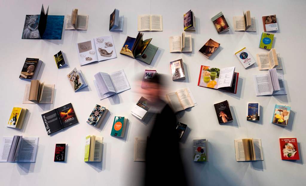 A visitor walks past a book display at the Frankfurt Book Fair on October 13, 2017 in Frankfurt am Main, western Germany. France is this year's guest of honour at the world's largest book fair, where more than 7,000 exhibitors from more than 100 countries