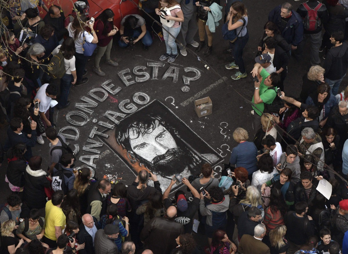 This file photo taken on September 01, 2017 shows people surrounding a portrait painted on the street of Santiago Maldonado --disappeared on August 1st during a Mapuche protest in Chubut province-- during a demonstration called by human rights association