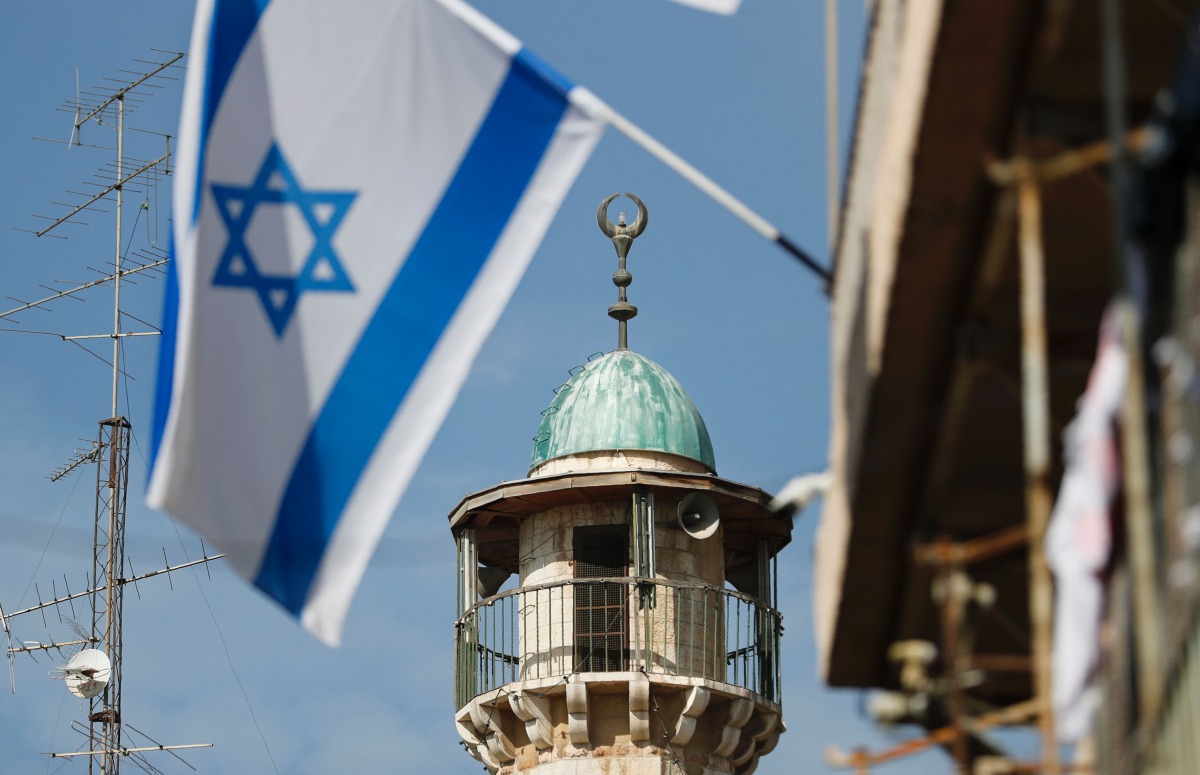 An Israeli flag waves in front of the minaret of a mosque in the Arab quarter of Jerusalem Old City on November 14, 2016 (AFP)