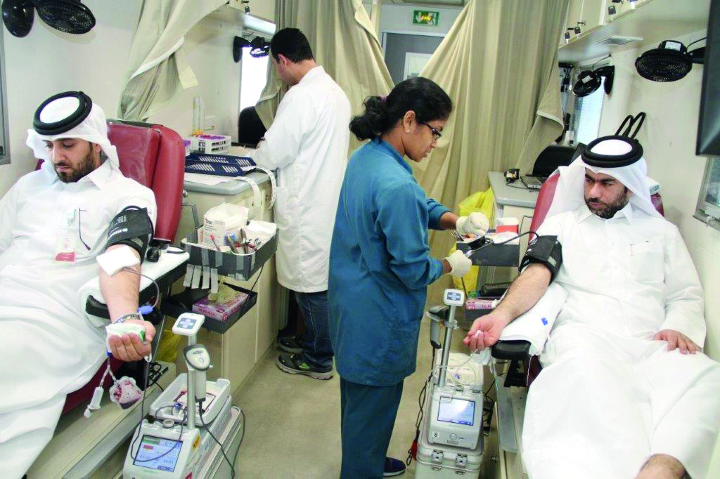 Employees donating blood aboard an HMC mobile vehicle in front of Kahramaa  headquarters in West Bay, yesterday.