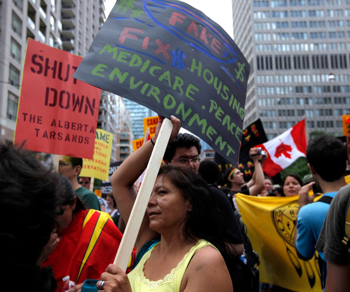 This file photo taken on June 24, 2010 shows a woman holding a sign as several hundred indigenous people march through the streets of Toronto to bring attention to the plight of indigenous peoples in Canada two days prior to the opening of the G20 Summit 