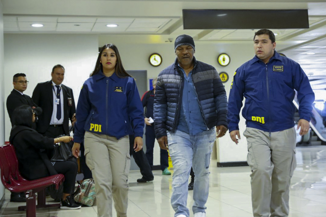 Handout picture realesed on November 9, 2017 by Chile's Investigation Police showing US former world heavyweight boxing champion Mike Tyson escorted by Chile's Investigations Police members at Santiago de Chile airport. AFP / Chile's Investigations Police