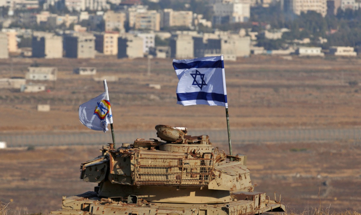 An Israeli flag flutters above the wreckage of an Israeli tank sitting on a hill in the Israeli-occupied sector of the Golan Heights on October 18, 2017 (AFP / Jalaa Marey) 