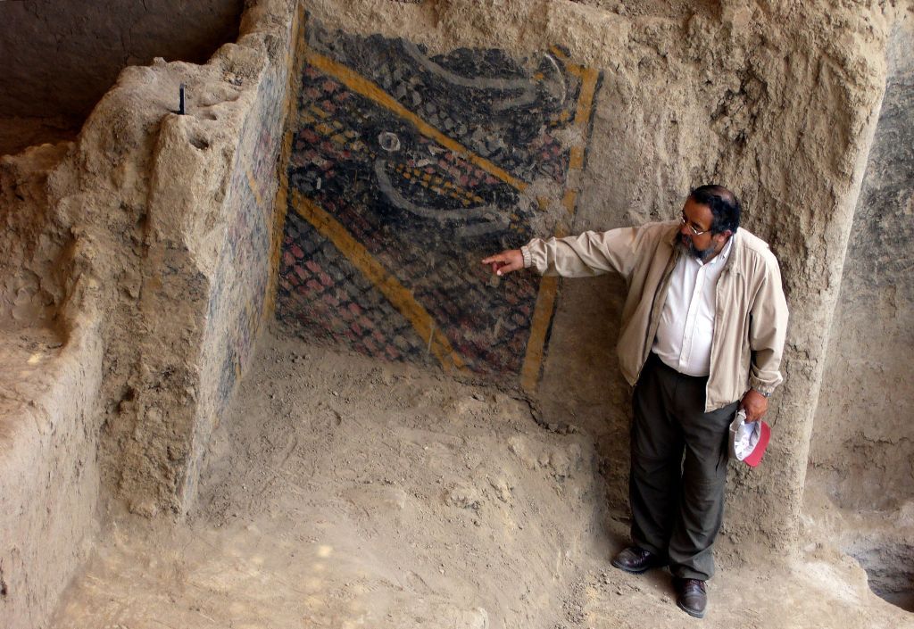 A handout file photo taken and released by Peruvian national news service Andina on November 10, 2007 shows Peruvian archaeologist Walter Alva pointing what is supposed to be the most ancient mural painting in America, in a temple in Chiclayo, more than 1