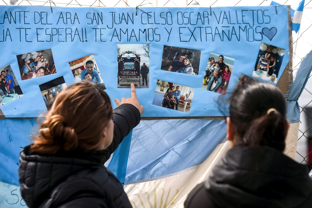 Women look at family pictures of missing Argentine submarine crew member Cesar Oscar Vallejos, hanging outside Argentina's Navy base in Mar del Plata, on the Atlantic coast south of Buenos Aires, on November 24, 2017. (AFP / EITAN ABRAMOVICH)