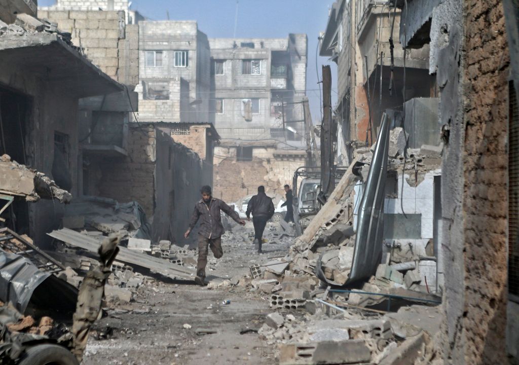 Syrian men run through an alley in the rebel-controlled town of Mesraba, in the eastern Ghouta region on the outskirts of the capital Damascus, on November 27, 2017, following reported bombardment by government forces.  AFP / ABDULMONAM EASSA