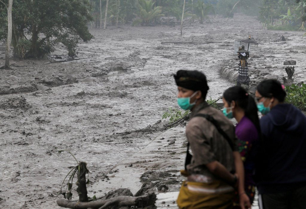 Villagers watch a river overflowing with water mixed with volcanic ash during the eruption of Mount Agung in Karangasem, Bali, Indonesia November 28, 2017. REUTERS/Johannes P. Christo
