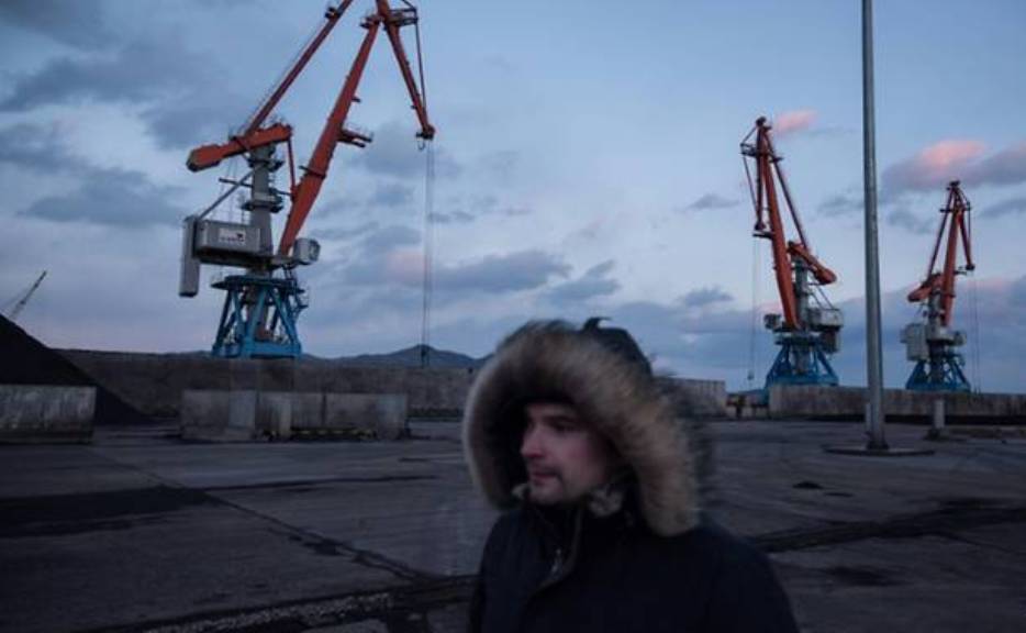 A Russian worker walking before cranes at Rajin's RasonConTrans coal port in North Korea. (Photo: AFP/Ed Jones).