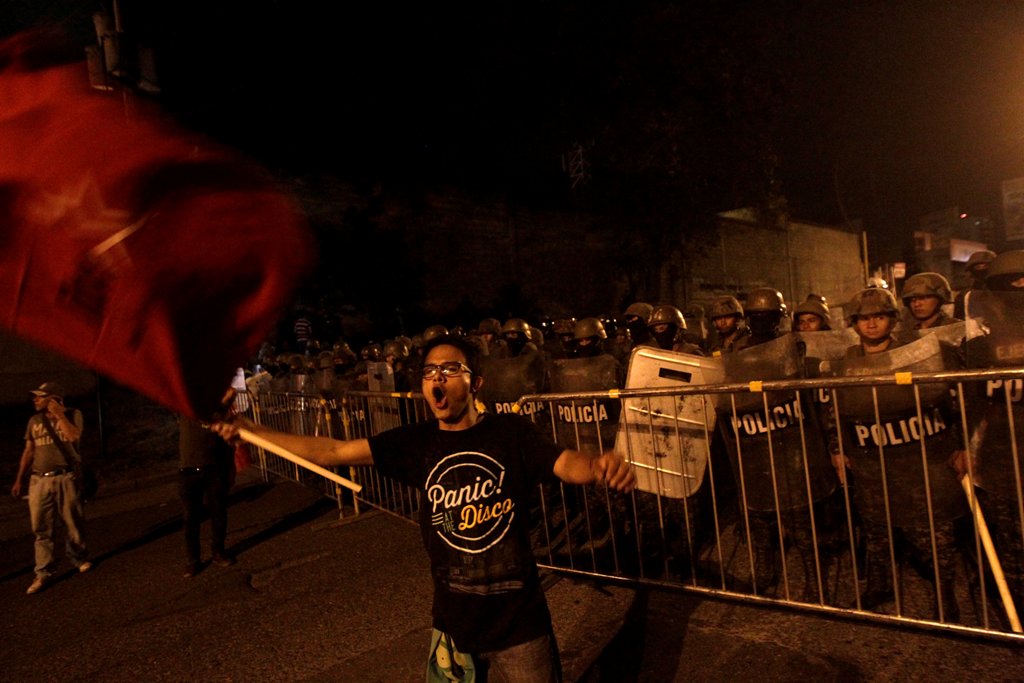 An opposition supporter waves a flag in front of soldiers during a protest over a contested presidential election with allegations of electoral fraud in Tegucigalpa, Honduras, December 8, 2017. REUTERS/Jorge Cabrera