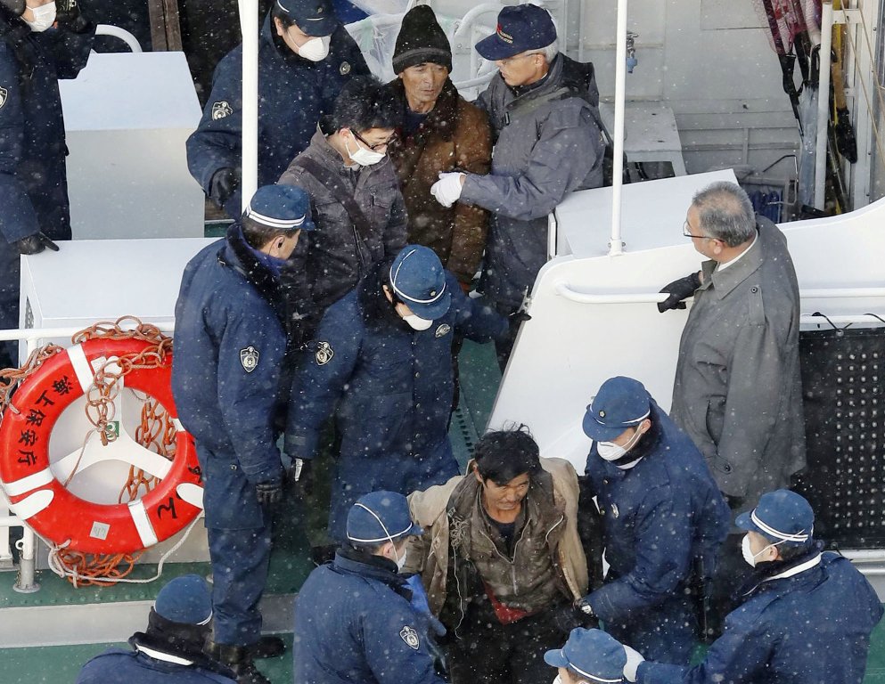 Japanese policemen escort the crew of a North Korean boat at a port in Hakodate, Japan December 9, 2017. Kyodo/via REUTERS