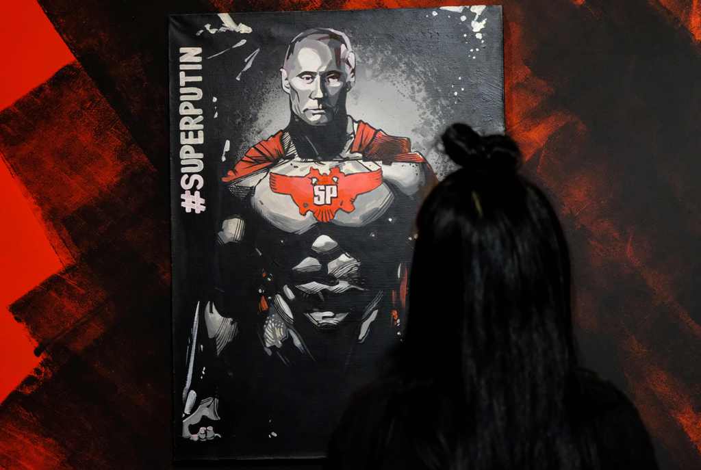 A woman looks at a painting depicting Russian president Vladimir Putin at the 