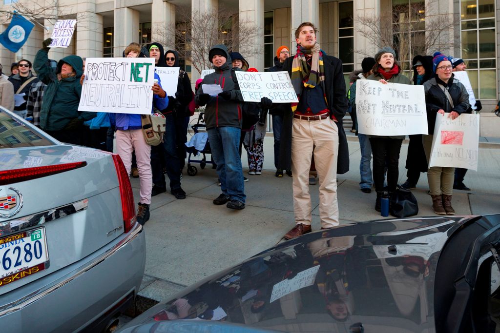 Demonstrators hold protest signs during a demonstration against the proposed repeal of net neutrality outside the Federal Communications Commission headquarters in Washington, DC on December 13, 2017. / AFP / Alex EDELMAN