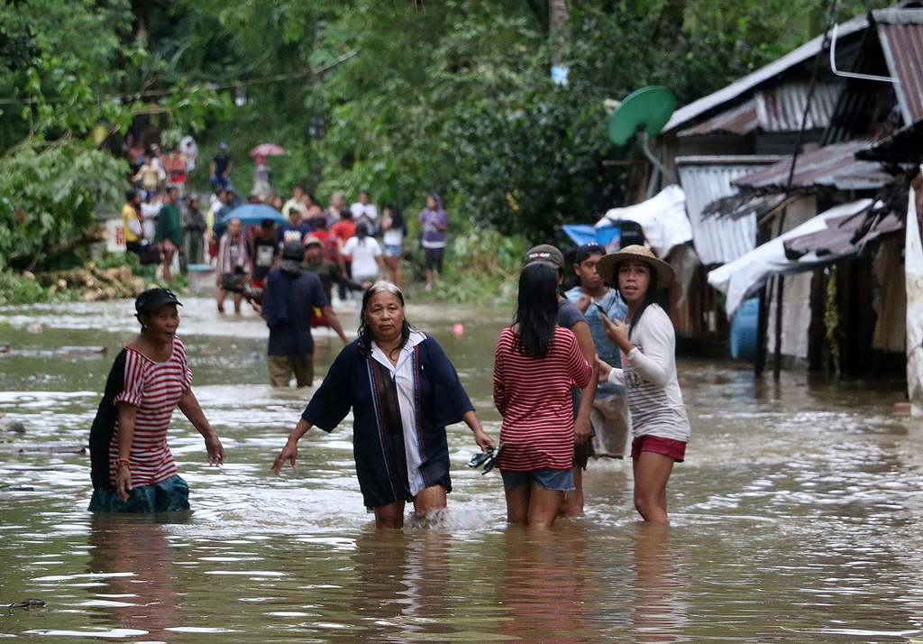 Villagers wade through a flooded street in Brgy Calingatngan, in Borongan, on easterm Samar in central Philippines on December 16, 2017. (AFP / ALREN BERONIO)