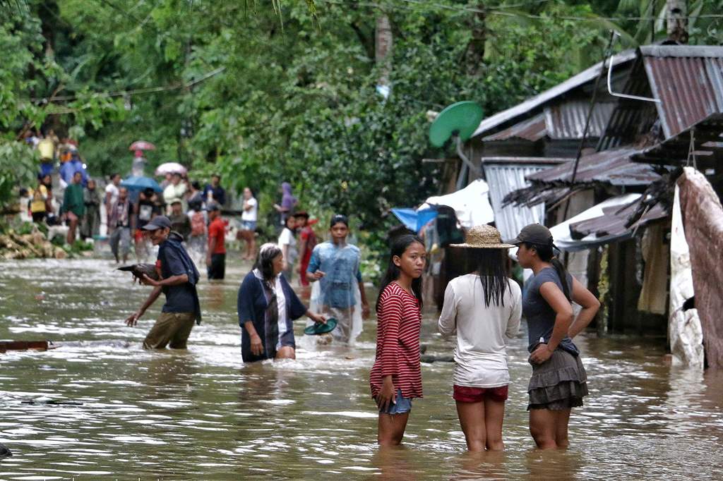 Villagers wade through a flooded street in Brgy Calingatngan, in Borongan, on easterm Samar in central Philippines on December 16, 2017. / AFP.