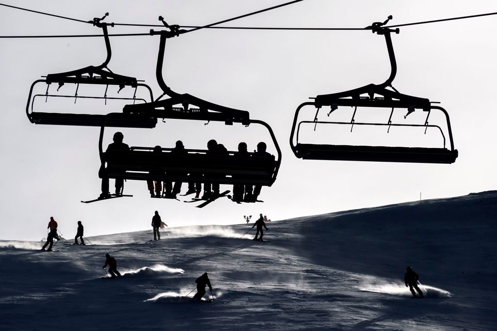 (FILES) This file photo taken on January 2, 2017 shows skiers sitting in a ski lift as others ski down a slope in the Swiss Alps resort of Les Crosets. AFP / FABRICE COFFRINI