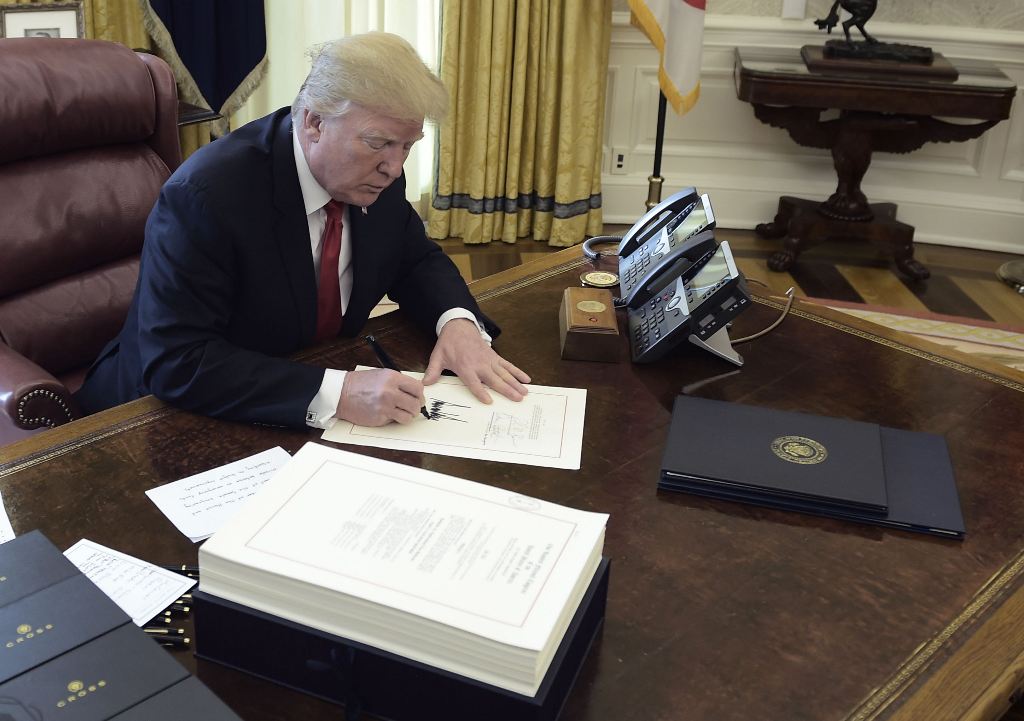 United States President Donald J. Trump signs a document during an event to sign the Tax Cut and Reform Bill in the Oval Office at The White House in Washington, DC on December 22, 2017. (AFP / Brendan SMIALOWSKI)